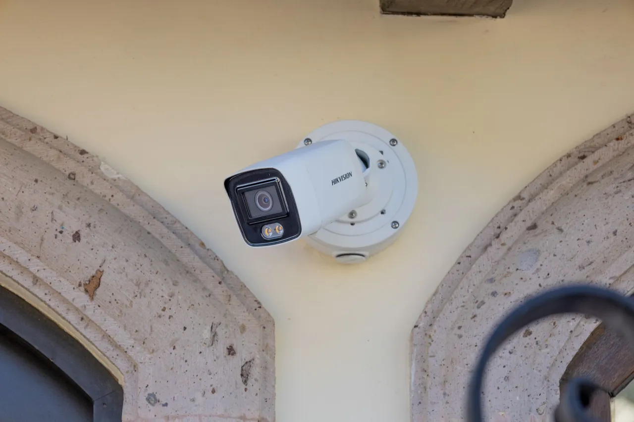Bullet camera on a yellow wall between two stone arches