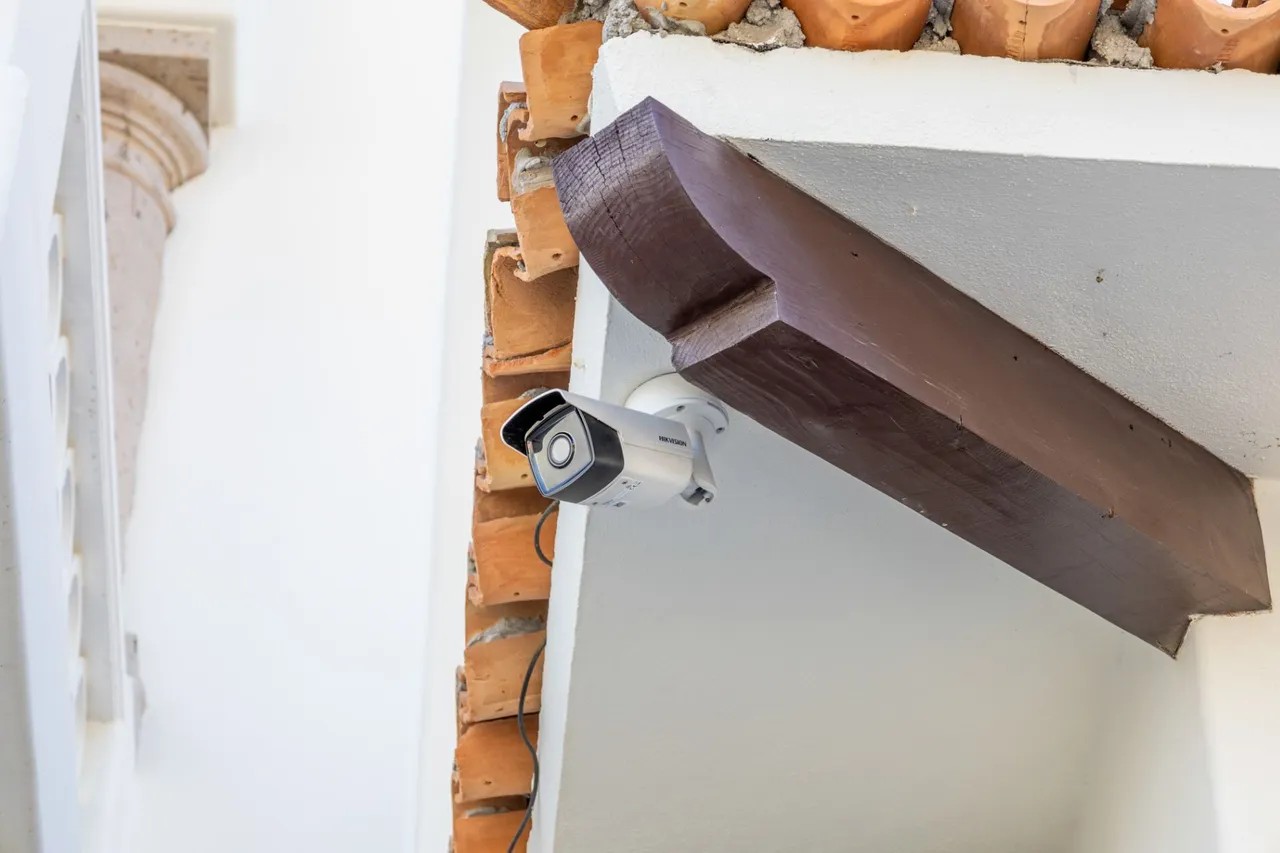 Bullet camera under a dark wooden beam, next to clay tiles