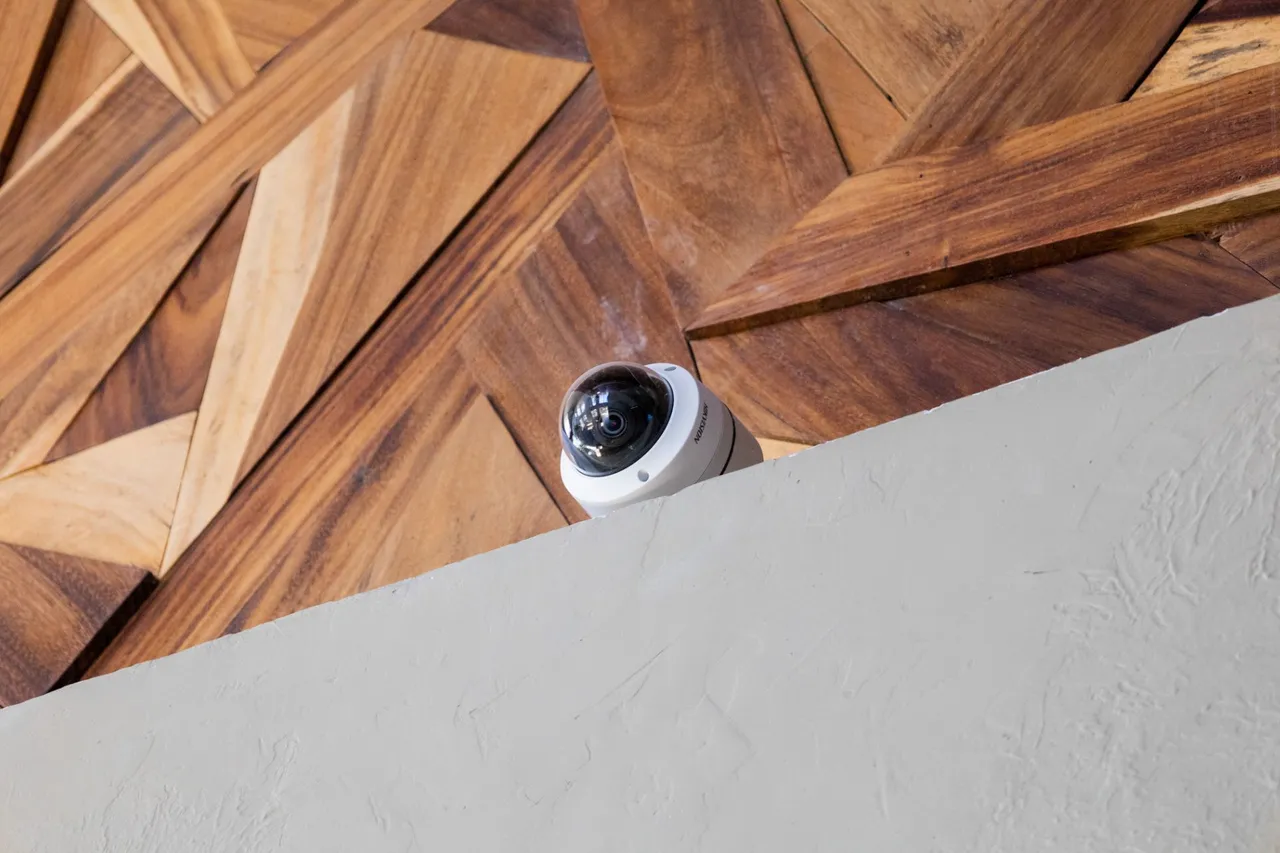 Dome camera at the edge of a wall, under a geometric wood ceiling