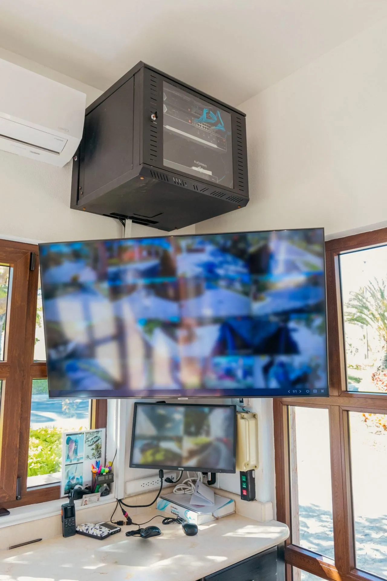Booth with a TV showing the cameras, a monitor and a wall-mounted network cabinet