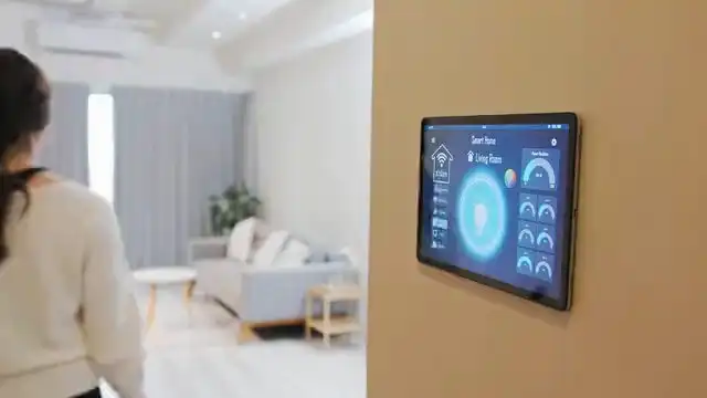 Woman walking through a living room with a wall-mounted smart-home panel