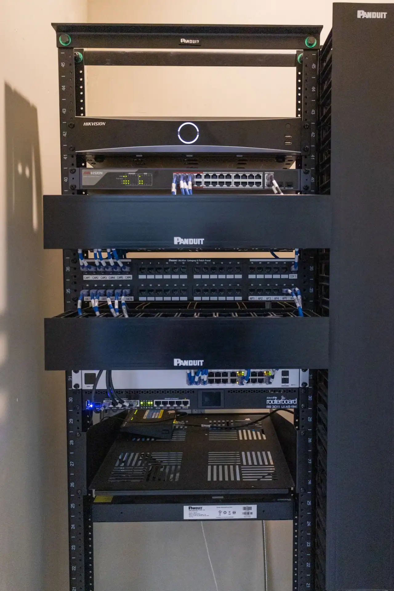 Communications rack with a video recorder, switch and neatly arranged patch panels